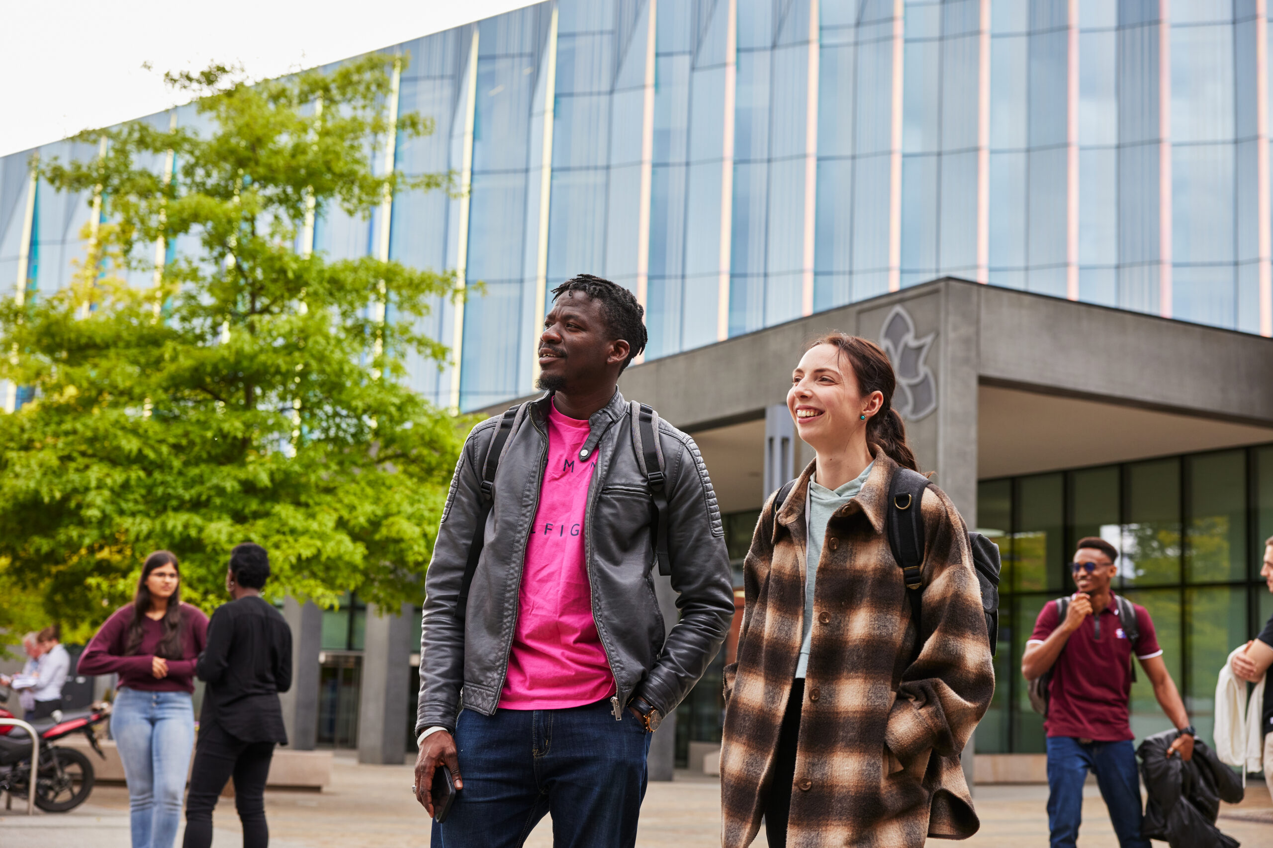 Students smiling infront of an MMU building